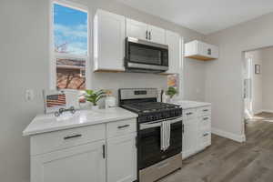 Kitchen featuring white cabinets, appliances with stainless steel finishes, and light hardwood / wood-style flooring