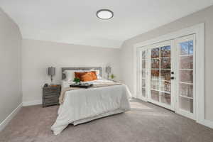 Bedroom with light carpet, access to exterior, and lofted ceiling