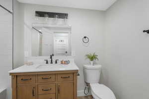 Bathroom featuring toilet, vanity, and curtained shower