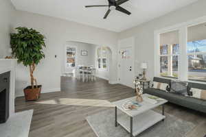 Living room with a brick fireplace, dark hardwood / wood-style floors, and ceiling fan