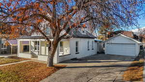 View of front of house featuring a garage, a sunroom, and an outdoor structure