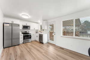 Kitchen featuring white cabinets, light wood-type flooring, sink, and stainless steel appliances