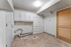 Clothes washing area featuring electric dryer hookup and cabinets