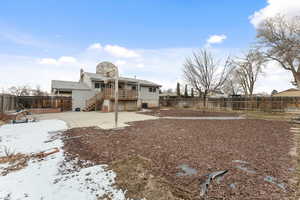 Snow covered back of property with a wooden deck and a patio