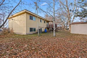 View of side of home with a wooden deck, a storage unit, and central AC