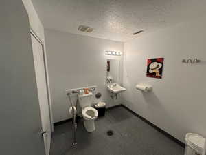 Bathroom featuring sink, a textured ceiling, and toilet