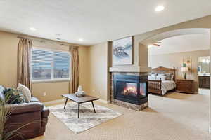 Primary suite living room featuring a multi sided fireplace, connected bathroom, and a textured ceiling