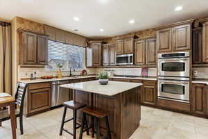 Kitchen with appliances with stainless steel finishes, backsplash, a kitchen island, a breakfast bar, and sink