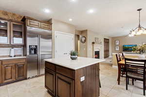 Kitchen featuring built in refrigerator, decorative light fixtures, light tile patterned flooring, and a kitchen island