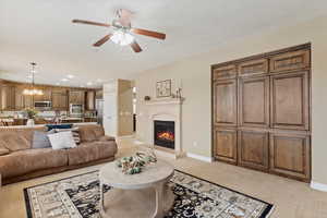 Living room with light colored carpet and ceiling fan with notable chandelier