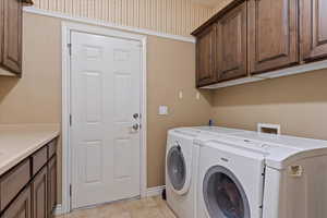 Washroom featuring cabinets, separate washer and dryer, and light tile patterned floors