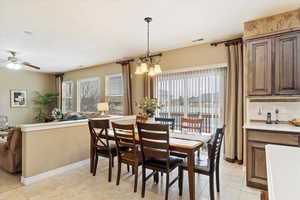 Tiled dining space with plenty of natural light and ceiling fan with notable chandelier