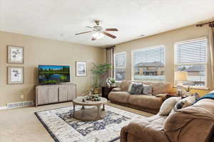 Family room featuring ceiling fan, a wealth of natural light, and light carpet