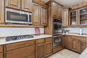 Kitchen featuring light tile patterned floors, stainless steel appliances, and decorative backsplash