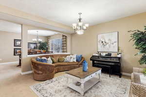 Carpeted living room with a chandelier