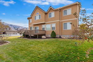 Back of house featuring a yard and a deck with mountain view