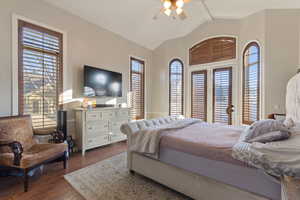 Bedroom featuring ceiling fan, hardwood / wood-style flooring, vaulted ceiling with beams, and multiple windows