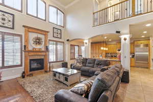 Living room with light hardwood / wood-style floors, a towering ceiling, sink, ornamental molding, and decorative columns