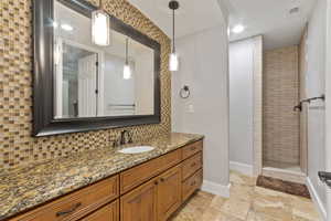 Bathroom featuring vanity, decorative backsplash, and a tile shower