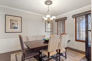 Dining room featuring dark hardwood / wood-style floors, ornamental molding, and a chandelier