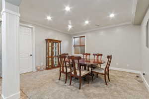 Carpeted dining area featuring ornamental molding