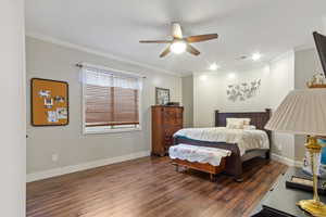 Bedroom featuring dark wood-type flooring, ceiling fan, and crown molding