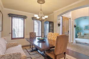 Dining area featuring an inviting chandelier, plenty of natural light, crown molding, and wood-type flooring