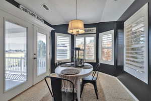 Dining space with a textured ceiling, lofted ceiling, and french doors