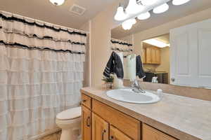 Bathroom with toilet, a shower with curtain, tile patterned floors, and vanity