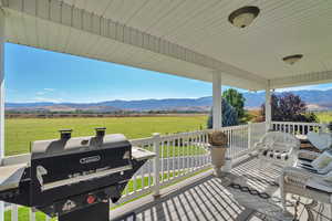 Wooden terrace with a rural view, a grill, a mountain view, and a lawn