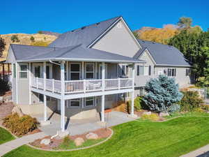 Back of property featuring a patio area, a lawn, and a mountain view