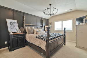 Carpeted bedroom featuring a textured ceiling, a notable chandelier, and vaulted ceiling