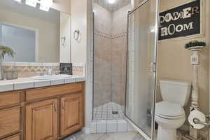 Bathroom featuring tile patterned floors, toilet, walk in shower, and vanity