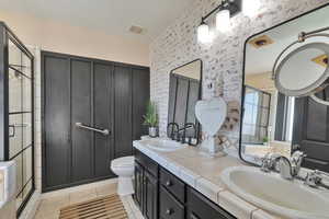 Bathroom featuring toilet, vanity, walk in shower, tile patterned floors, and a textured ceiling