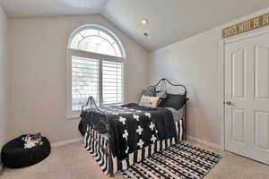 Bedroom featuring a textured ceiling, lofted ceiling, and light colored carpet