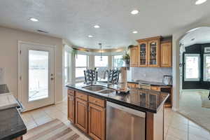 Kitchen featuring pendant lighting, stainless steel dishwasher, sink, a kitchen island with sink, and light carpet