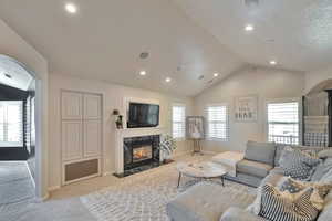 Living room with light colored carpet, lofted ceiling, and a fireplace