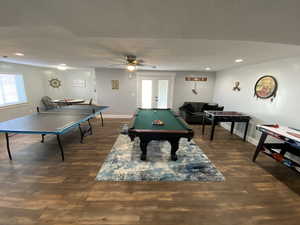 Game room with dark hardwood / wood-style floors, ceiling fan, french doors, and billiards