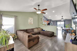 Living room with wood-style flooring, ceiling fan, and vaulted ceiling