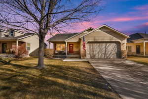 Ranch-style home with a garage, a porch, and a yard