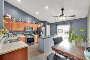 Kitchen featuring ceiling fan, vaulted ceiling, and appliances with stainless steel finishes