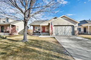 View of front of property featuring a front lawn, a garage, and a porch