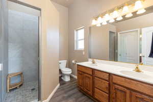 Bathroom featuring wood-type flooring, toilet, walk in shower, and vanity