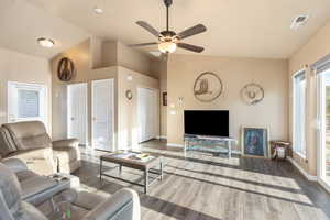 Living room with ceiling fan, lofted ceiling, and hardwood / wood-style flooring