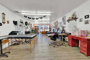 Home office featuring light hardwood / wood-style floors, a textured ceiling, and ornamental molding