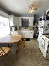 Kitchen featuring white cabinetry, ceiling fan, tasteful backsplash, white appliances, and sink