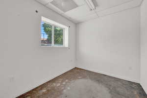 Empty room with a drop ceiling and concrete floors