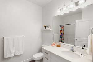 Bathroom featuring toilet, vanity, and a shower with shower curtain