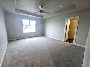 Carpeted spare room with ceiling fan and a raised ceiling