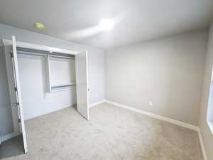 Unfurnished bedroom featuring a closet and light carpet